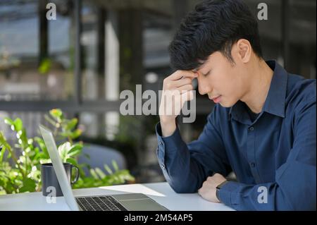 Young businessman stressed about his project and have a headache during work time. side view Stock Photo