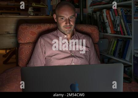 Man sitting in armchair working on his laptop, Bavaria, Germany Stock Photo
