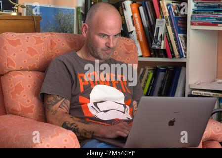 Man sitting in an armchair and working intently on a laptop, Bavaria, Germany Stock Photo