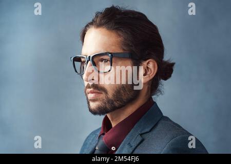 Clarity is key. Studio shot of a handsome young man looking thoughtful against a grey background. Stock Photo