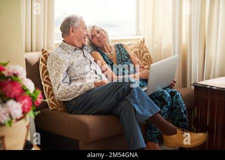 Learning about technology and loving it. a senior couple using a laptop together on the sofa at home. Stock Photo