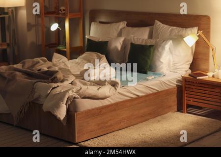 Bed with electric heating pad in bedroom at night Stock Photo
