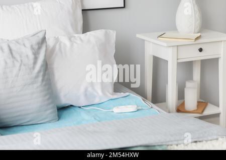 Bed with electric heating pad in bedroom Stock Photo