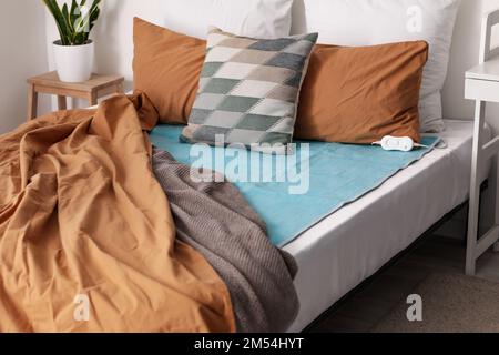 Bed with pillows and electric heating pad in bedroom Stock Photo
