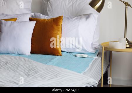 Bed with electric heating pad in bedroom Stock Photo