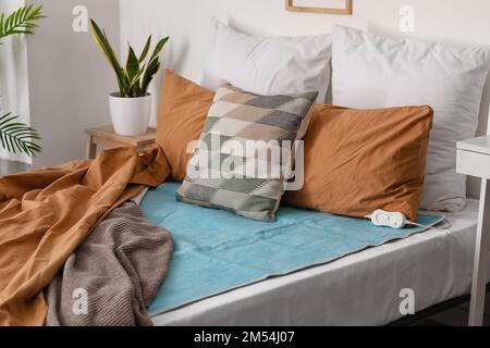 Bed with electric heating pad in bedroom Stock Photo