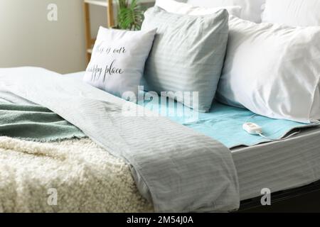 Bed with electric heating pad in bedroom Stock Photo