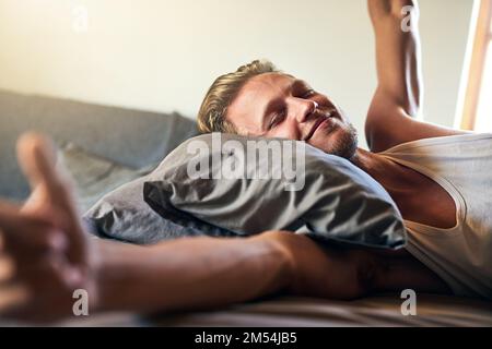 Waking up to a good morning. a young man stretching while waking up in bed. Stock Photo