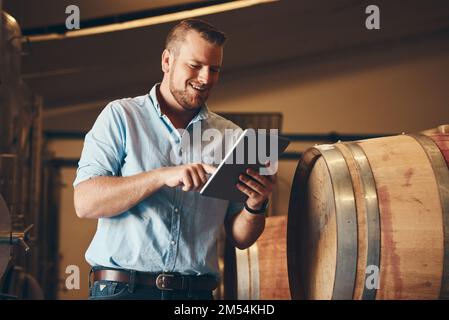 Getting so many positive reviews online. a handsome young male sommelier using his digital tablet at work. Stock Photo