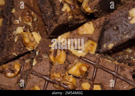 Chocolate brownies topped with walnuts piled on a serving platter. Homemade baked goods, isolated abstract closeup with selective focus. Stock Photo