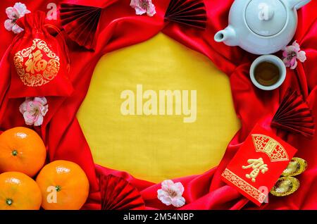 Chinese new year dinner with tea set, red envelope packet or ang bao(word mean congratulations), ingots, oranges and red bag (word mean wealth) on red Stock Photo