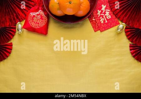 Chinese new year concept with red envelope packets or ang bao (word mean auspice), oranges, ingots and red bag (word mean wealth) on gold empty space Stock Photo