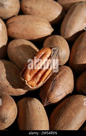 close up of pecan nuts in shell, one nut cracked, background  Stock Photo