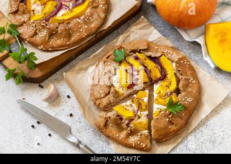 Healthy homemade wholegrain vegan vegetarian pie (galette) with pumpkin and ricotta cheese on a stone table. Homemade pumpkin Galette. Stock Photo