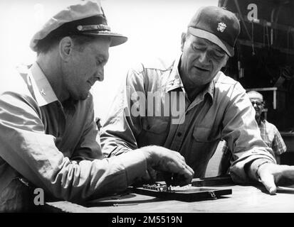 KIRK DOUGLAS and JOHN WAYNE on set location candid playing Chess during a break in filming of IN HARM'S WAY 1965 director OTTO PREMINGER novel James Bassett music Jerry Goldsmith Otto Preminger Films (Sigma Productions) / Paramount Pictures Stock Photo