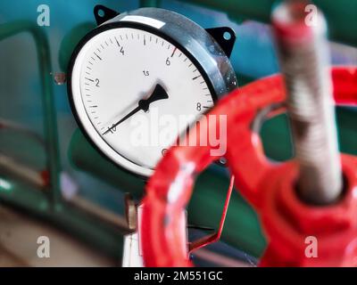 Red valve and pressure sensor on the gas supply or heating pipe.. Stock Photo