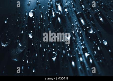 Round drops of water on dark background. Through transparent drops of water pass rays of light. View from top. Beautiful back for screensaver. Abstract background.. Stock Photo