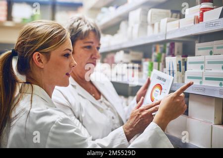Equipped with the necessary tools to improve your health. two pharmacists using a digital tablet while checking stock on the shelf. Stock Photo