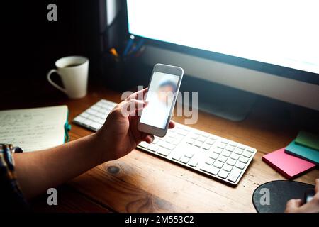 He works hard for his family. a designer looking at a photo on his cellphone while working at his computer late in the evening. Stock Photo