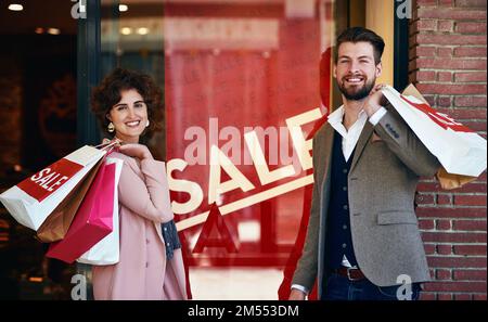 We never miss a sale. a young couple out on a shopping spree. Stock Photo