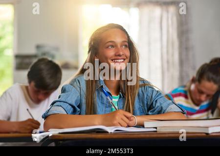 I know Im going to ace this test. a young schoolgirl smiling while sitting at her desk in class. Stock Photo