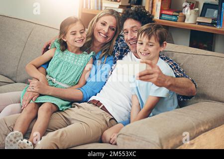 Taking selfies fam style. a happy family taking a selfie together on a mobile phone at home. Stock Photo