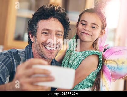 Selfies with my sweet little girl. a happy father and daughter taking a selfie together on a mobile phone at home. Stock Photo