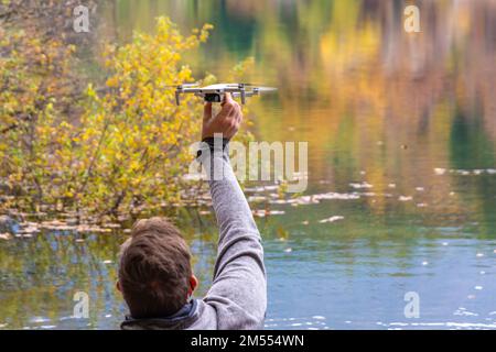 Man flying drone over Monticolo lake in South Tyrol, Appiano, Bolzano province, Trentino Alto Adige, northern Italy- Europe Stock Photo