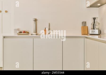 a kitchen with white cupboards and appliances on the counter top in front of the sink is an open door Stock Photo