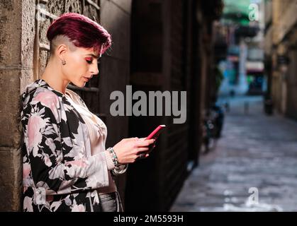 Woman with short hair using a mobile in the street Stock Photo