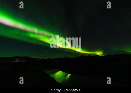 Northern lights pink and green light beams over the lake Stock Photo