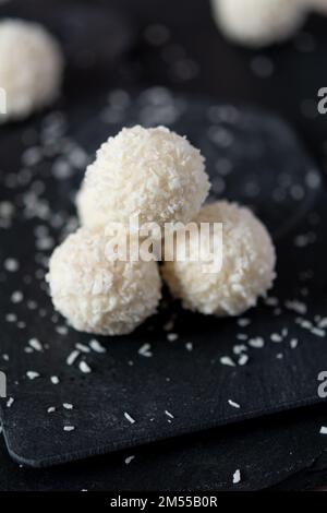 White coconut pralines on a black granite background. Selective focus, shallow depth of field Stock Photo