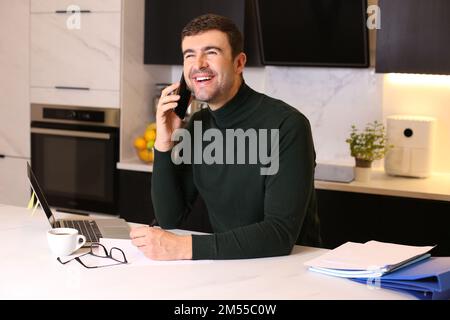 Handsome man calling by phone from home office Stock Photo