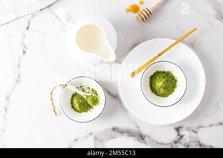 matcha tea powder in white ceramic bowls and a special bamboo measuring spoon on a marble table. top view. traditional Japanese tea Stock Photo