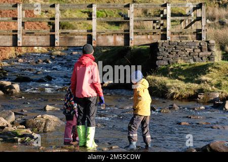 Pen-Y-Fan, Brecon Beacons, Wales – Monday 26th December 2022 – UK Weather - Family walkers enjoy a Boxing Day walk across a stream at the base of Pen-Y-Fan on a bright crisp morning in the Brecon Beacons in south Wales with local temperatures of 4c. Photo Steven May / Alamy Live News. Stock Photo