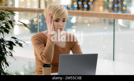 Caucasian middle aged mature 40s business woman with laptop working problems with payment computer breakdown error losing feeling frustrated bad news Stock Photo