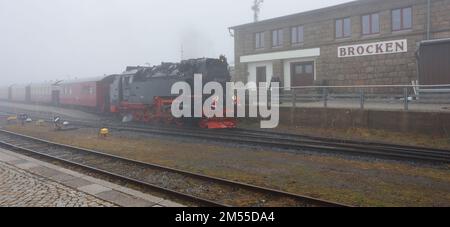 Schierke, Germany. 26th Dec, 2022. A train of the Harzer Schmalspurbahn HSB arrives at the Brocken station.Due to the holidays there are limited train services at the HSB. Drizzle and fog are currently dominating the weather on the Brocken. Only a few hikers are on the summit. Credit: Matthias Bein/dpa/Alamy Live News Stock Photo