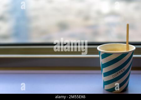 Takeaway cup of coffee placed on table near train window during trip in morning Stock Photo