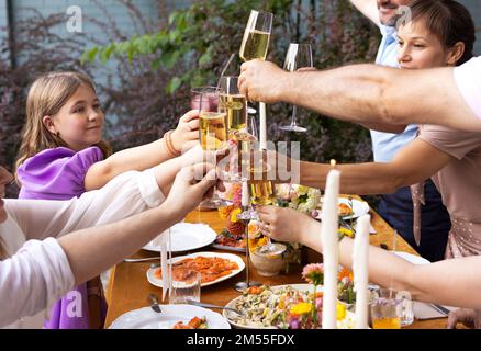 Many people saying cheers and showing their champagne glasses full of sparkling wine to each other whilst enjoying an outdoor wedding party on a backy Stock Photo