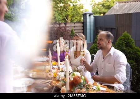 Many people saying cheers and showing their champagne glasses full of sparkling wine to each other whilst enjoying an outdoor wedding party on a backy Stock Photo