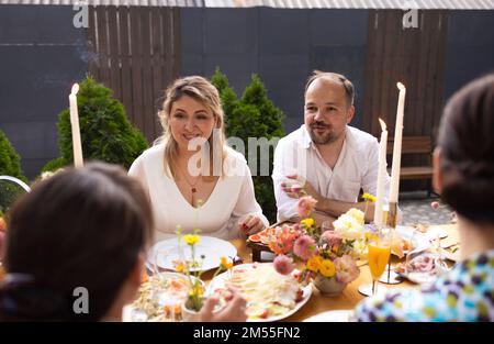 Many people saying cheers and showing their champagne glasses full of sparkling wine to each other whilst enjoying an outdoor wedding party on a backy Stock Photo