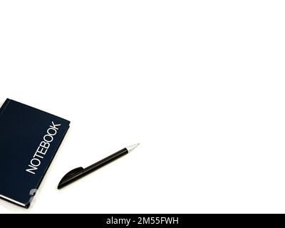 Hard covered notebook and black pen on a plain white background with copy space. Stock Photo