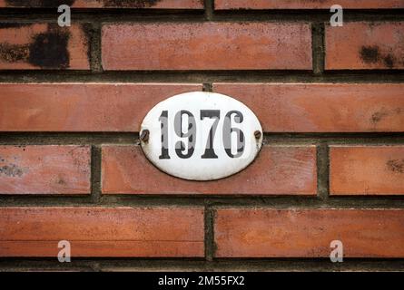 Sign with the house number 1976 on the background of the wall. High quality photo Stock Photo
