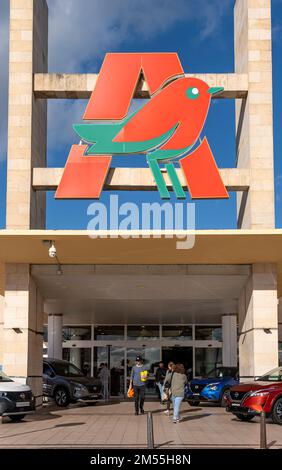 Marratxi, Spain; december 16 2022: Main facade of the multinational supermarket chain Alcampo, part of the Auchan group, with Nissan cars on display, Stock Photo