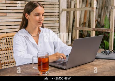 Attractive young woman using laptop computer sit in office typing on laptop. Stock Photo