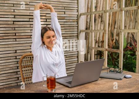 Young happy positive business woman sit indoors in co working using laptop computer. Stock Photo