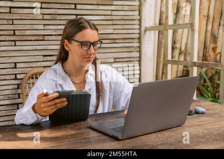 Attractive young woman using digital tablet and laptop computer in summer office Stock Photo