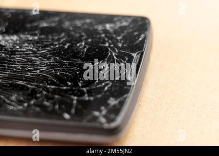 Broken black touchscreen of a mobile phone close-up on a brown surface. Macro Stock Photo