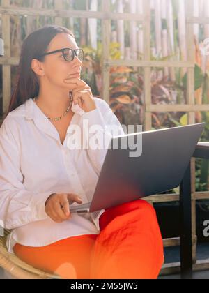 Concentrated at work. Confident young woman working on laptop while sitting near window in creative office or cafe Stock Photo