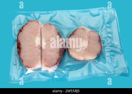 Slices of blue shark fish in vacuum packed sealed for sous vide cooking isolated on blue background Stock Photo